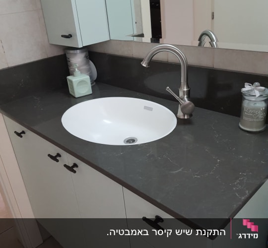 משטח שיש כהה עם כיור עגול וברז מתכת